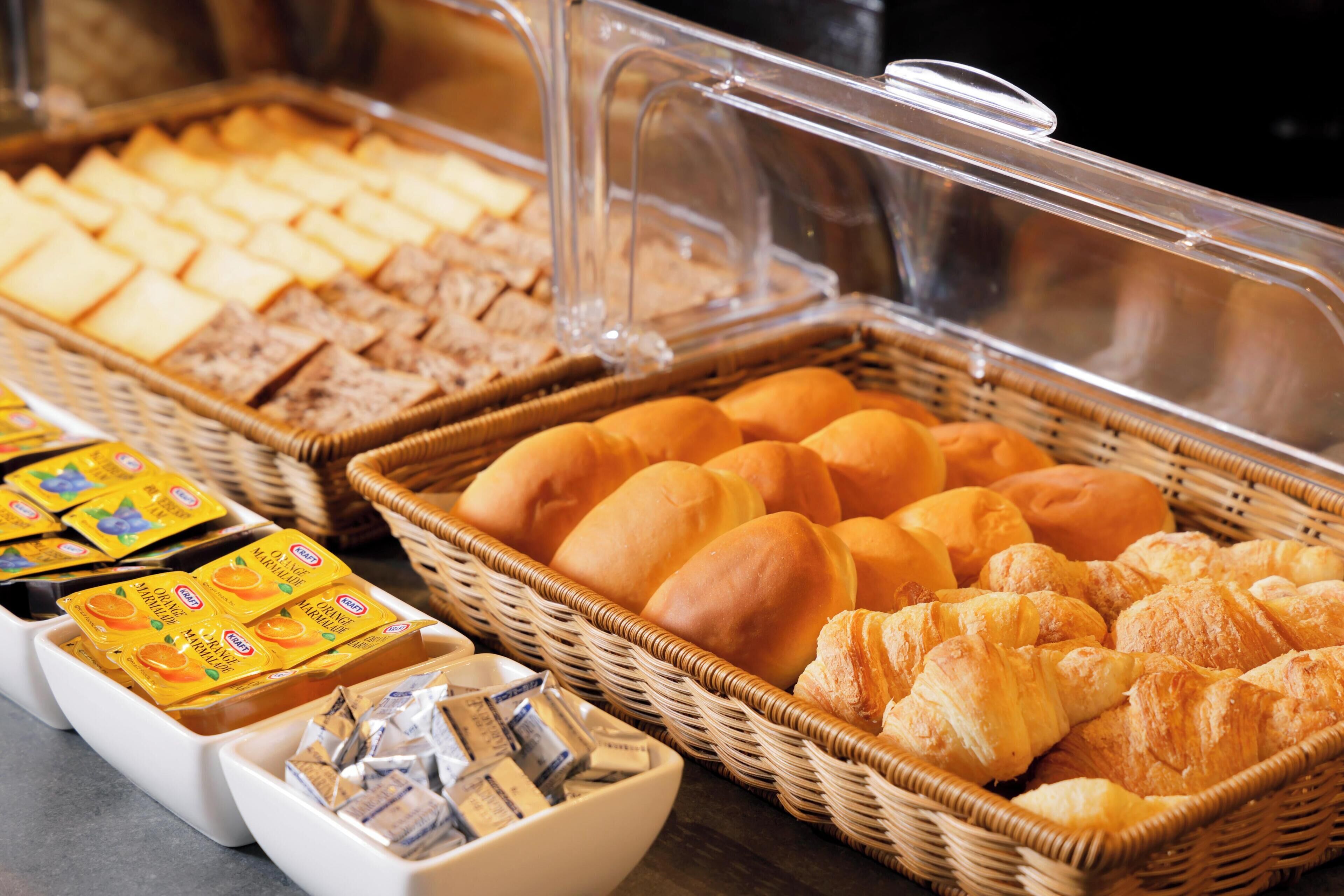 Een buffet met diverse etenswaren, zoals brood, gebak en verpakte snacks.