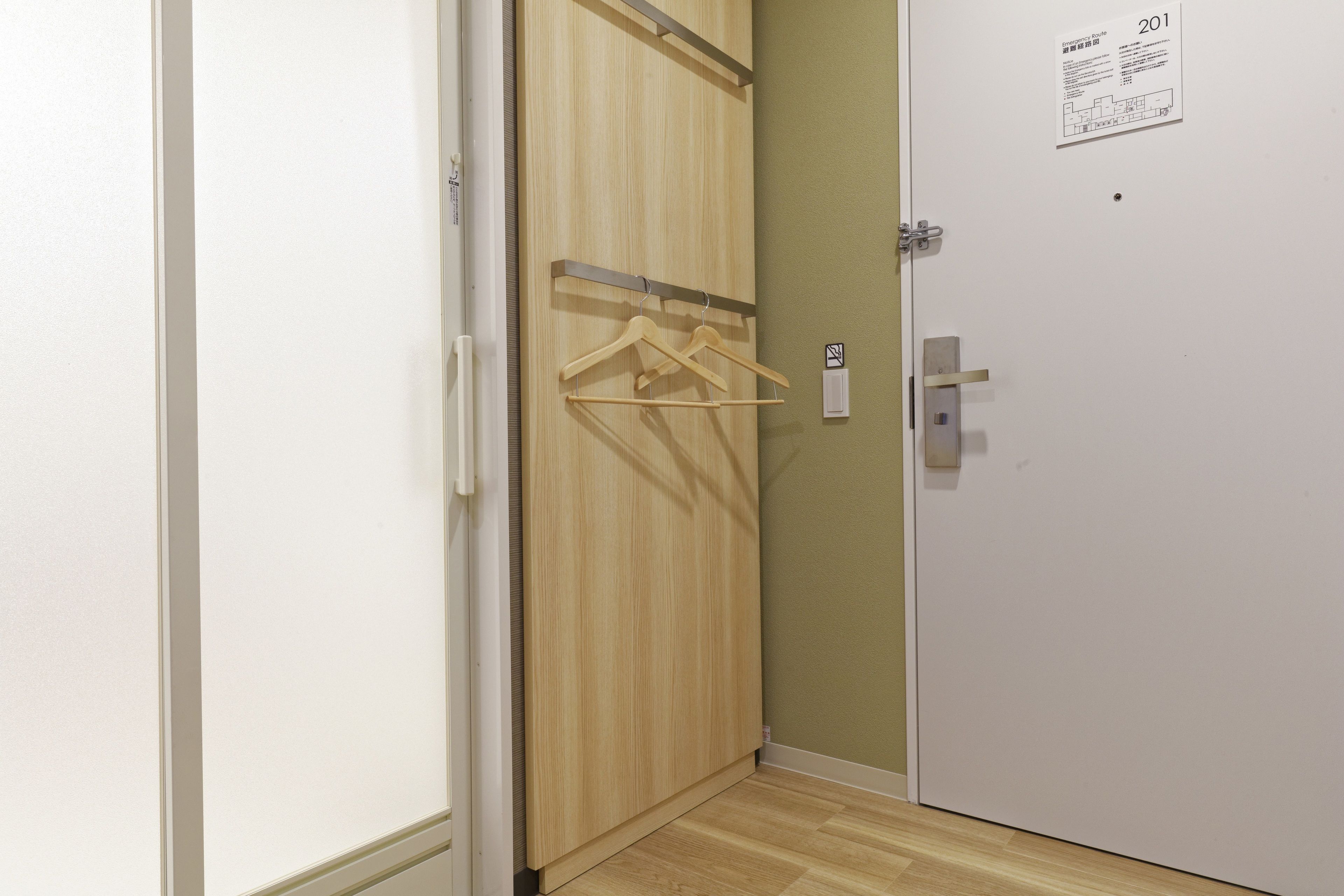 Un couloir avec une armoire en bois, une porte blanche et un interrupteur fixé au mur.
