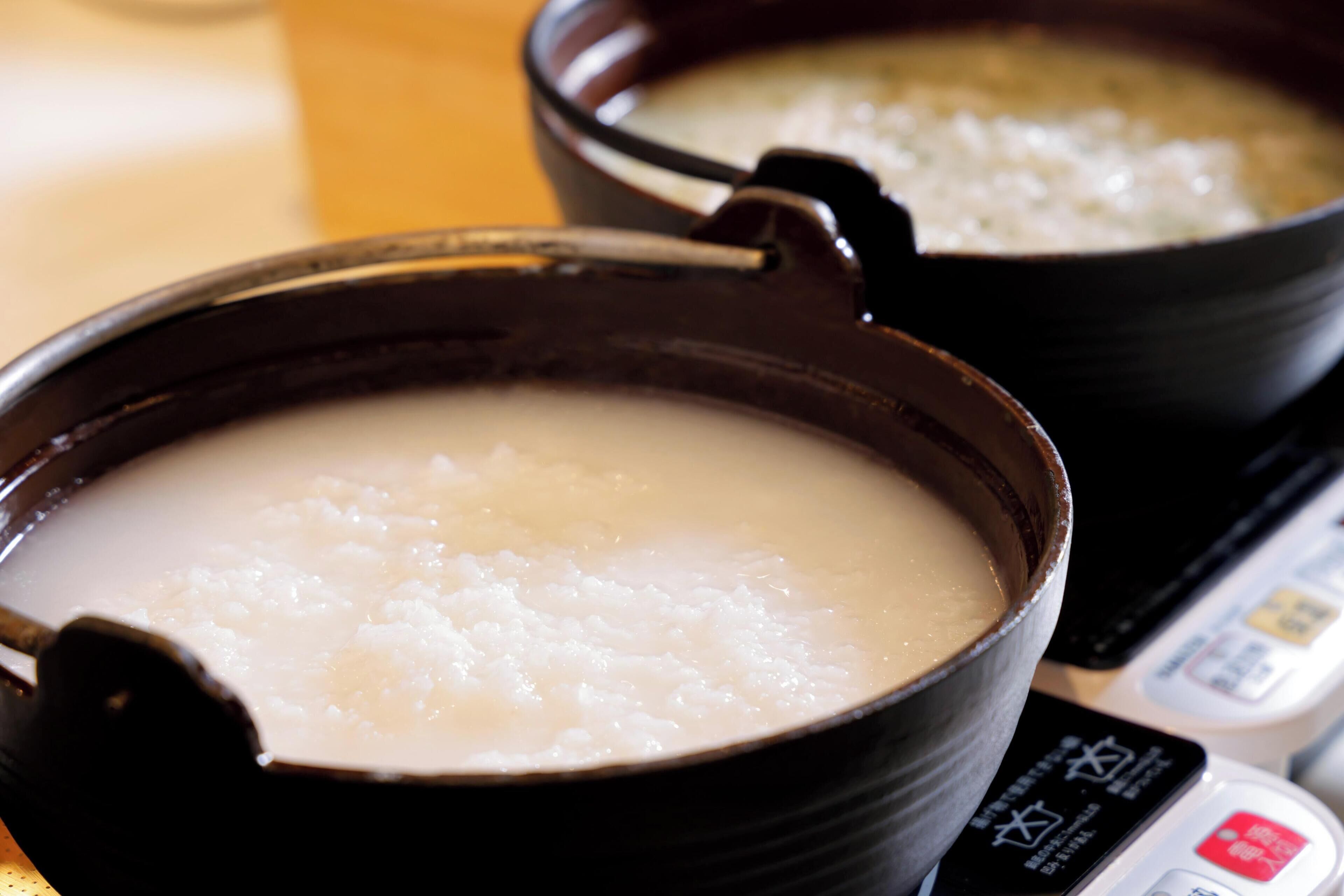 Two black bowls of white porridge on a stove.