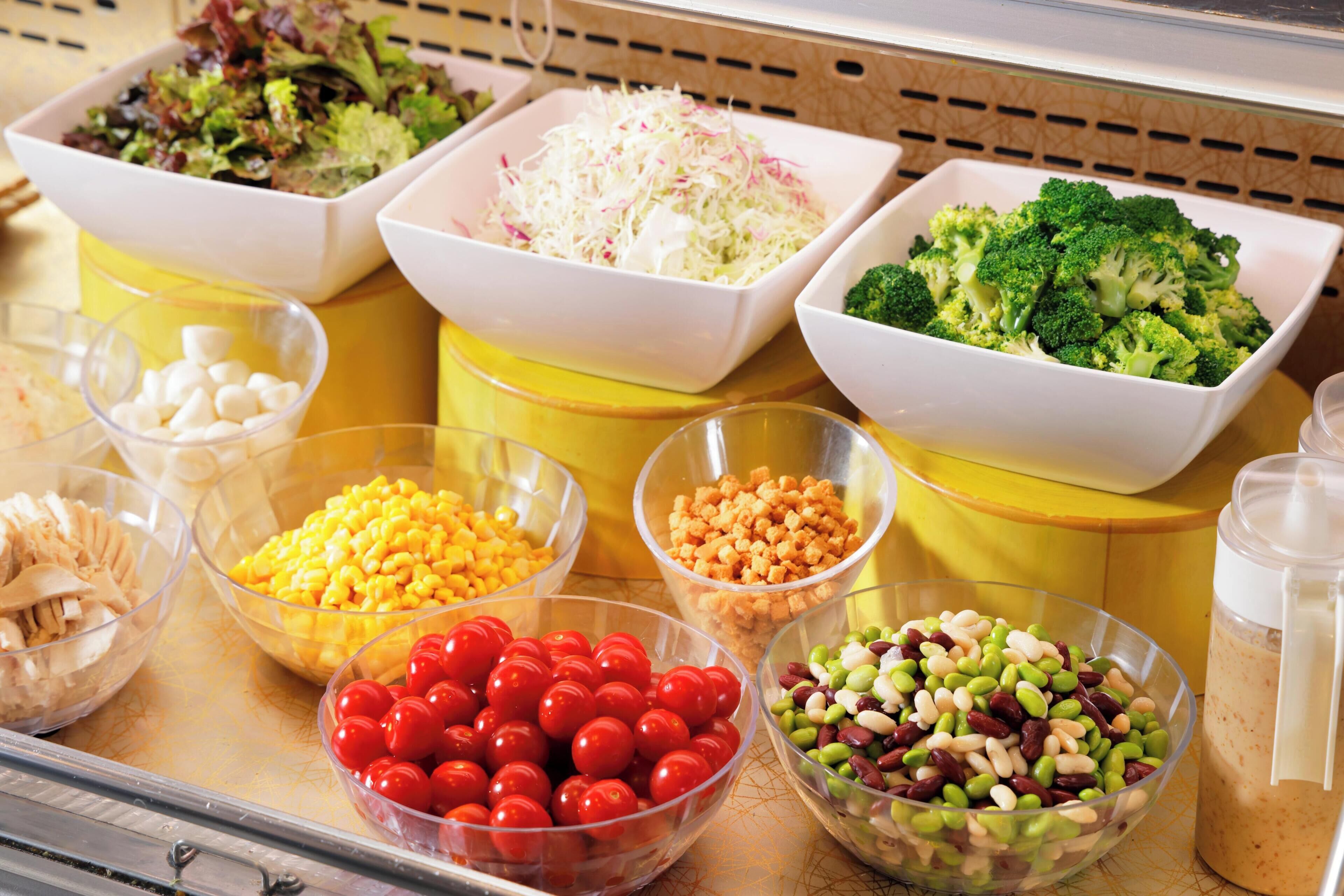 A buffet with various food items including salads, vegetables, and legumes.