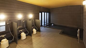 A modern bathroom with multiple shower stalls, a large bathtub, and a tiled floor.