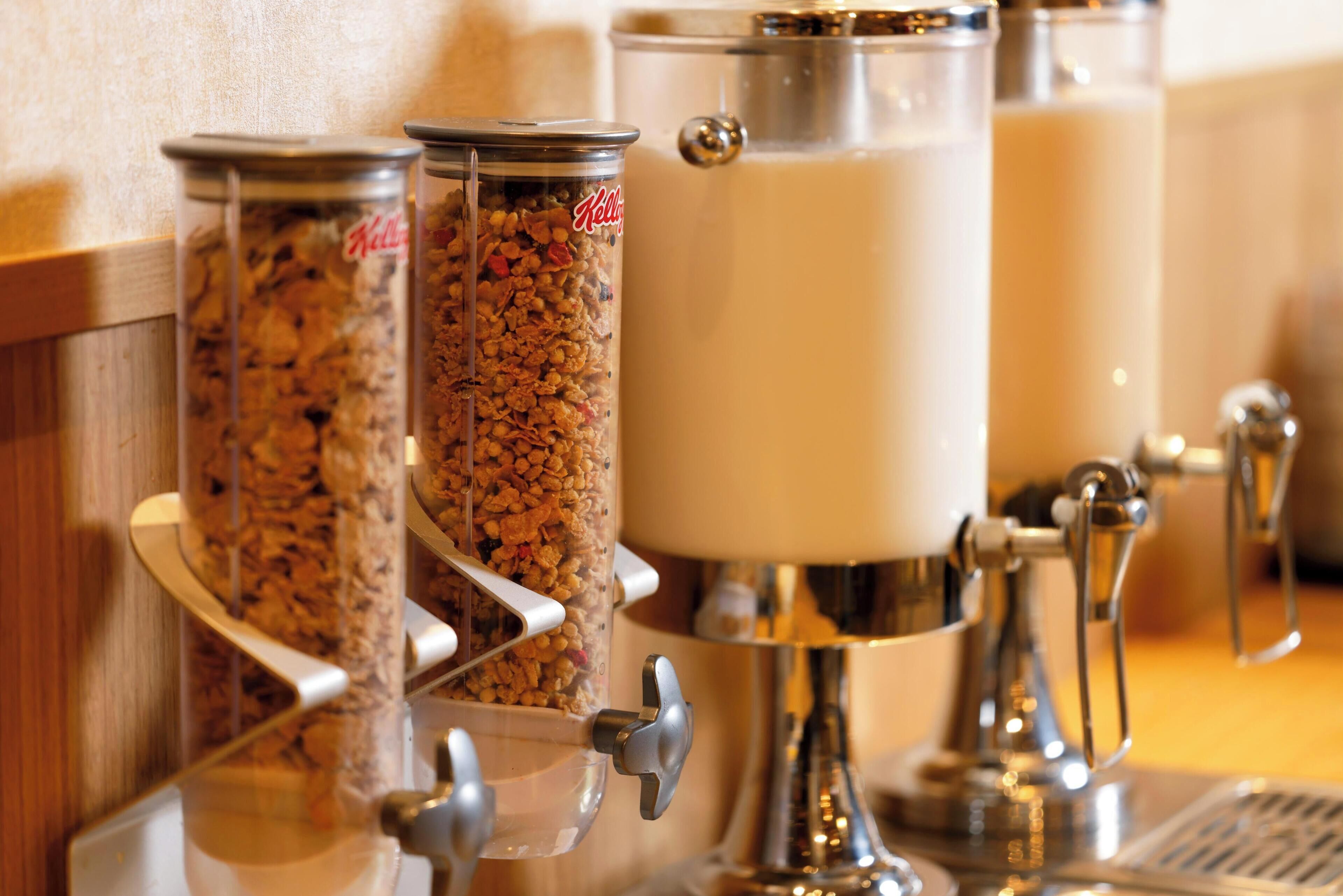 A food dispensing station with containers of granola and milk.