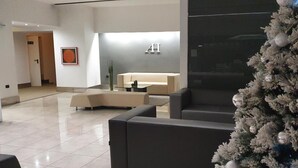 Um lobby moderno com balcão de recepção, área de estar e um pinheiro de Natal.