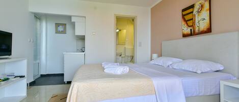 A hotel room with a bed, a TV, a desk, and a painting on the wall.