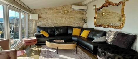 A modern living room with a black leather sofa, a round coffee table, and a patterned rug.
