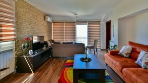Una sala de estar moderna con una pared de ladrillo, un sofá, una mesa de centro y un televisor.