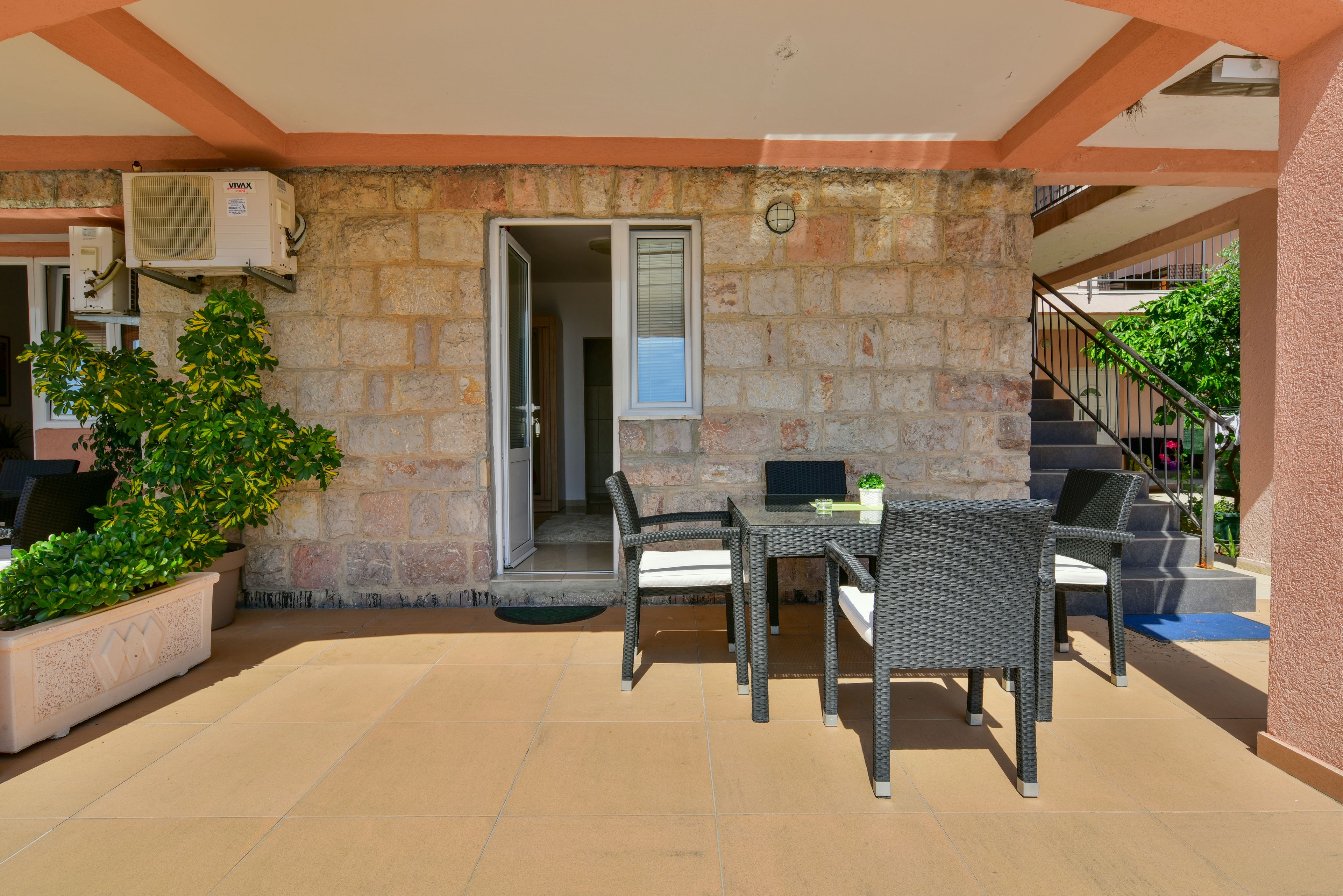 Un patio al aire libre con un muro de piedra, una mesa con sillas y una planta en maceta.