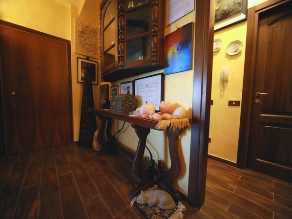 Interior de madera con piso de madera oscura, un banco de madera con asiento tejido y un perro pequeño descansando sobre una alfombra.