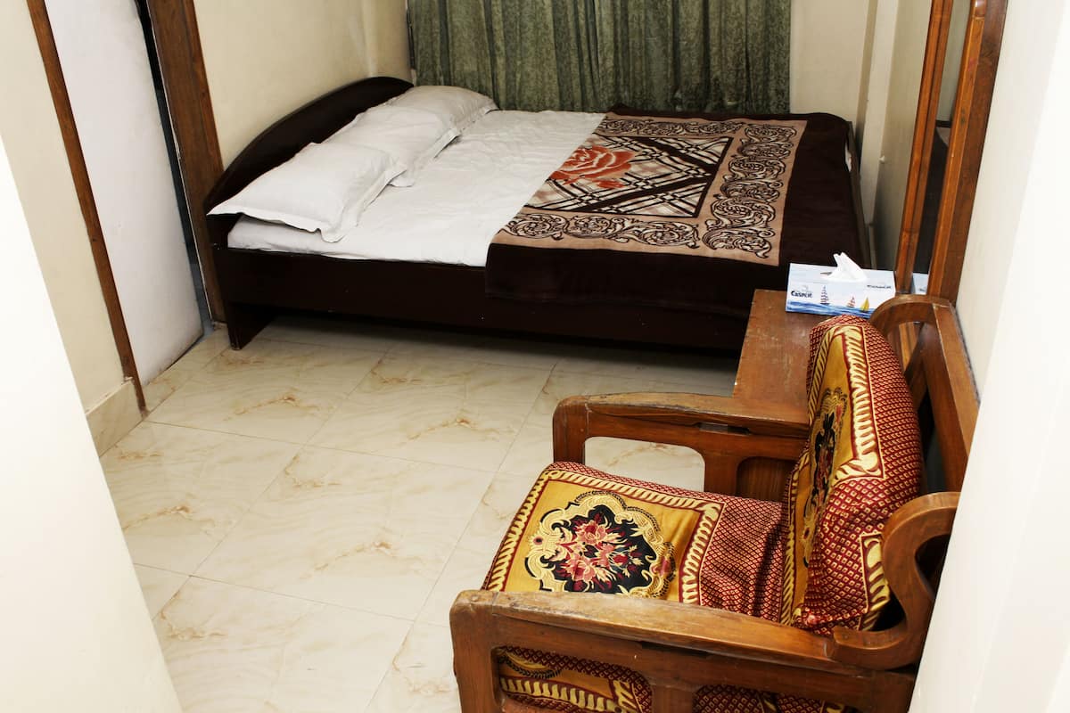 A room with a bed, a wooden chair, and a table.