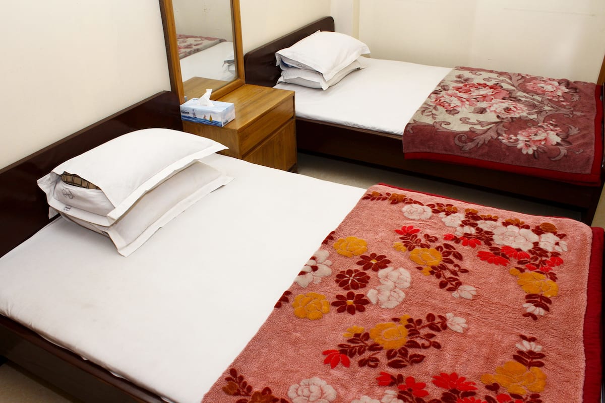 A hotel room with two single beds, each with a different style of bedding.