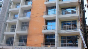 Un immeuble à plusieurs étages doté de balcons et d’une enseigne indiquant « Shapnaloy Studio Apartments ».