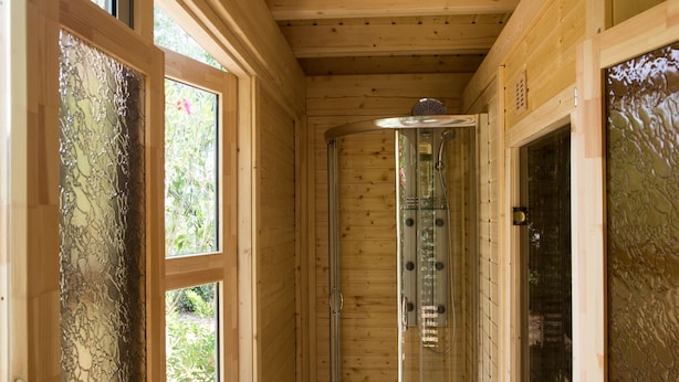 A wooden interior with a glass-enclosed shower, large windows, and a wooden floor. - Agriturismo Benvenuti (Roccastrada)