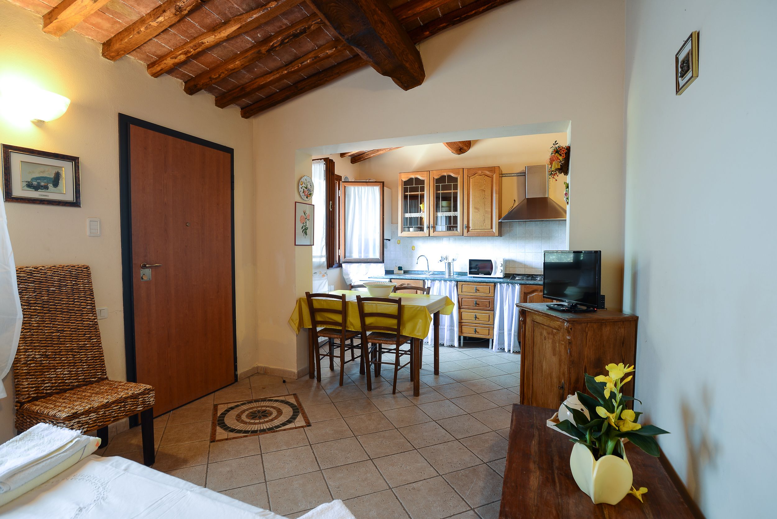 A room with a wooden ceiling, a dining area with a table and chairs, a TV, and a wooden cabinet.