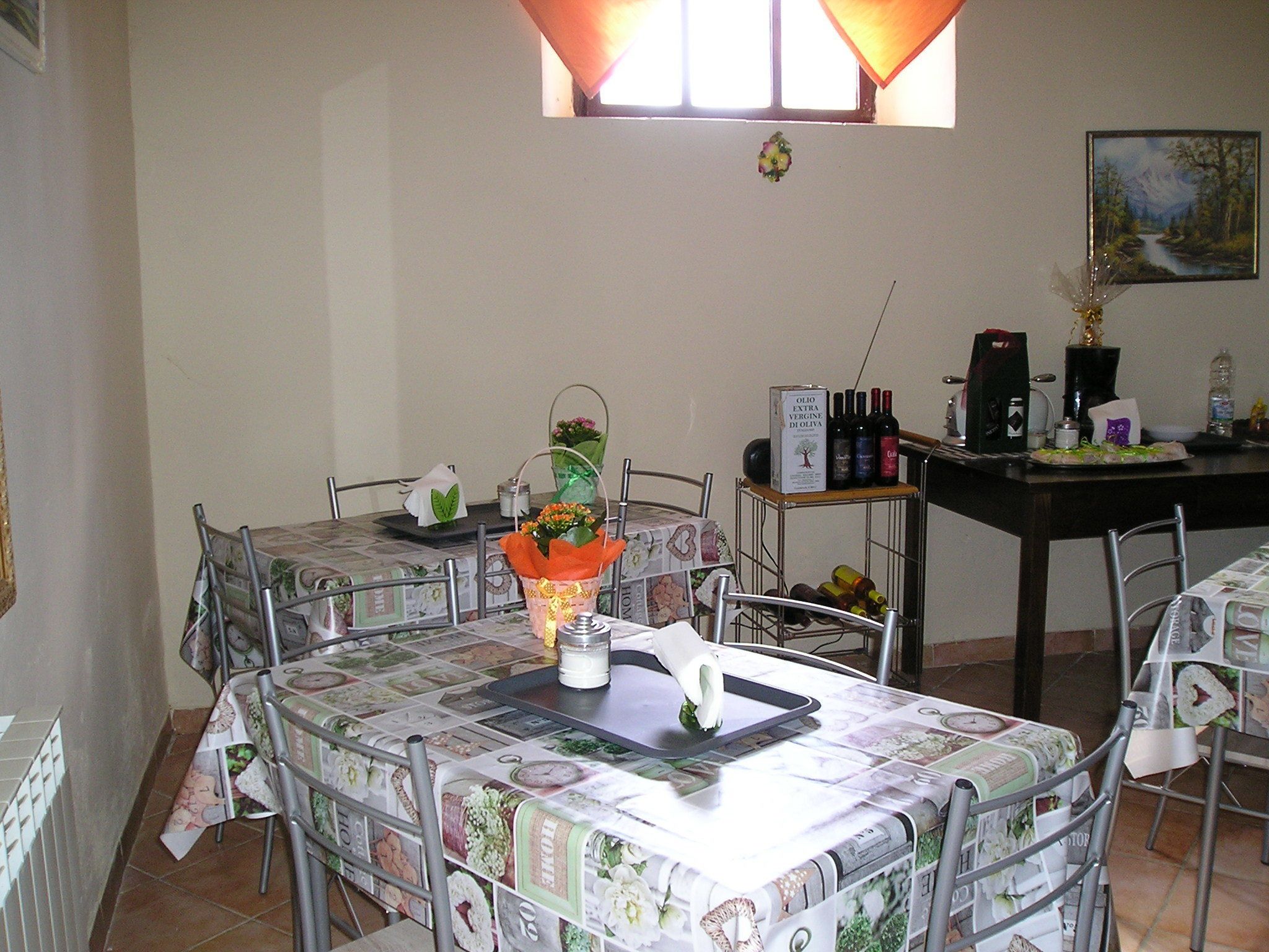 A dining area with a table set for two, a vase with flowers, and a wine rack with bottles.
