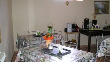 A dining area with a table set for two, a vase with flowers, and a wine rack with bottles.