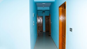 Un couloir étroit aux murs bleus, avec une porte en bois sur le côté droit.