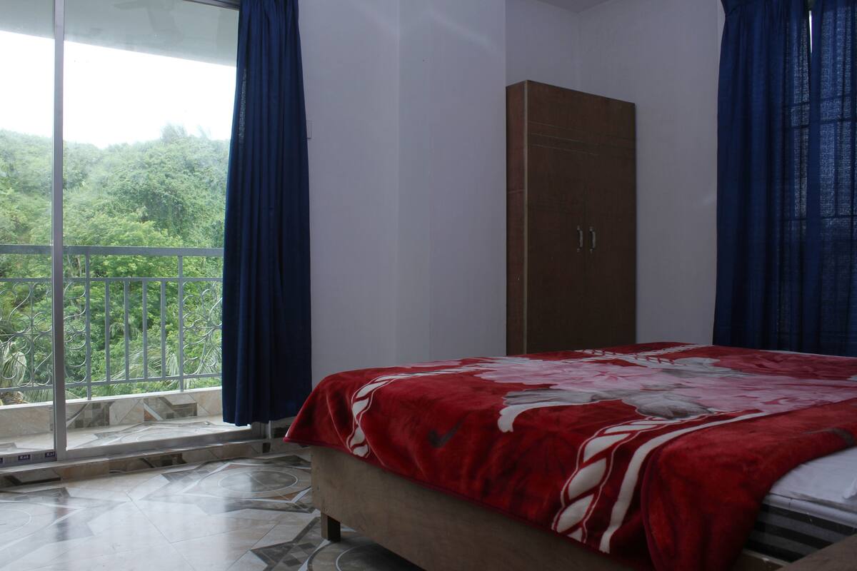 A bedroom with a bed, a wardrobe, and a balcony with curtains.