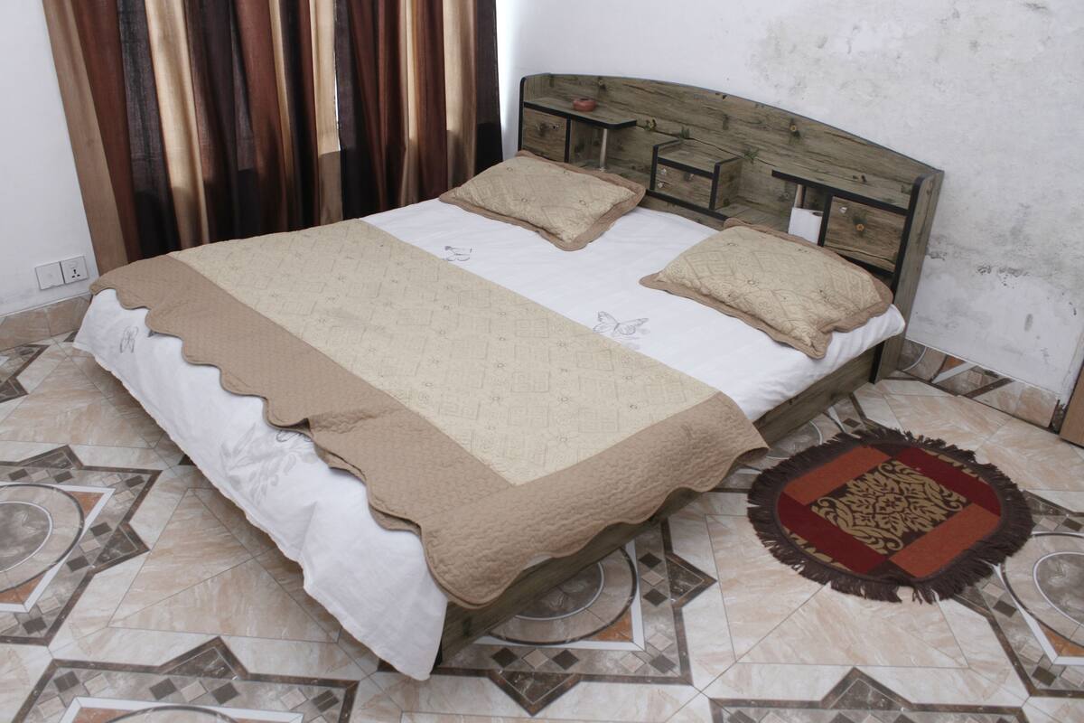 A bed with a wooden headboard, a bedside table, and a patterned floor.