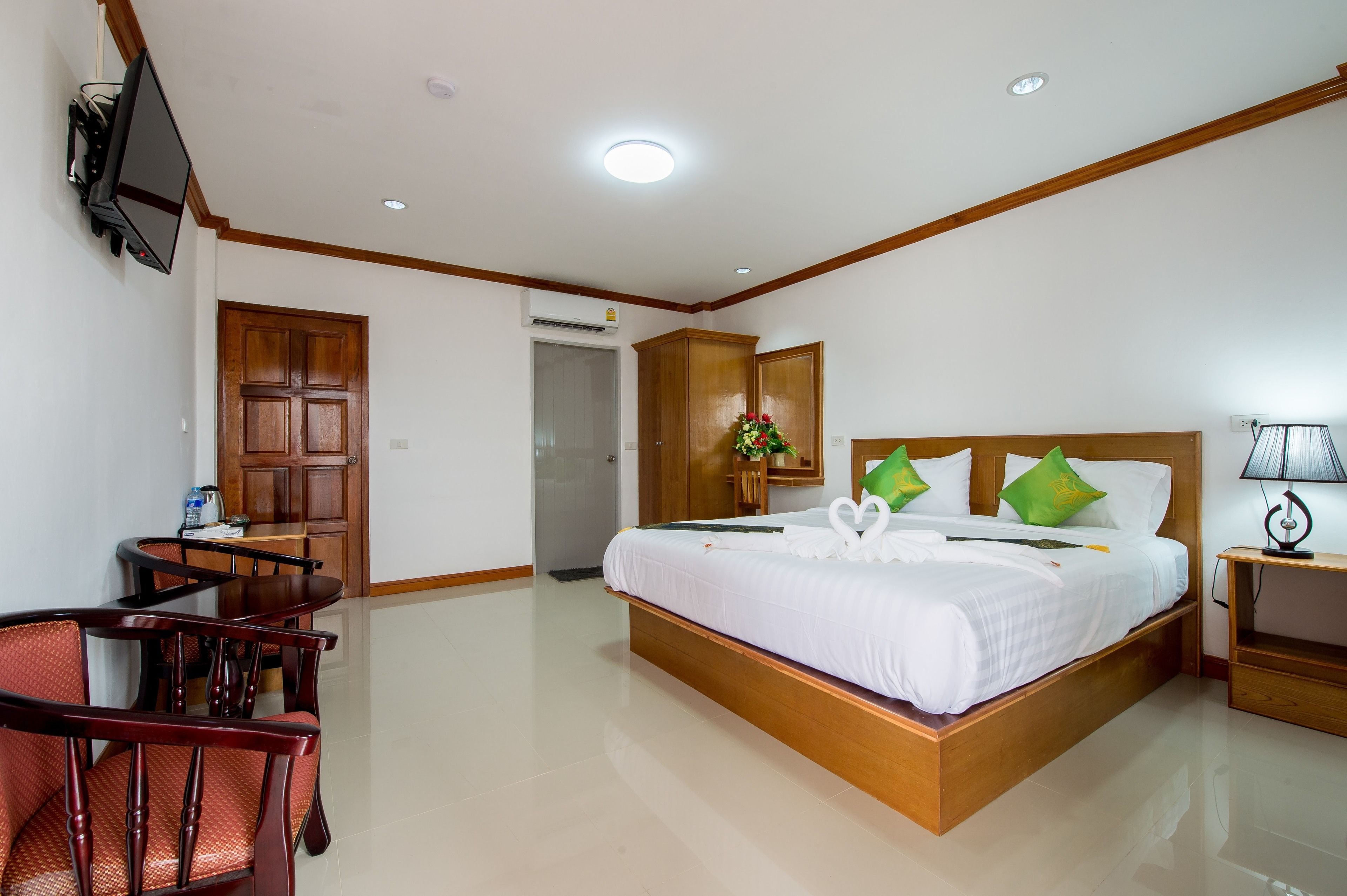 A hotel room with a bed, a desk, a chair, a TV, and a nightstand.