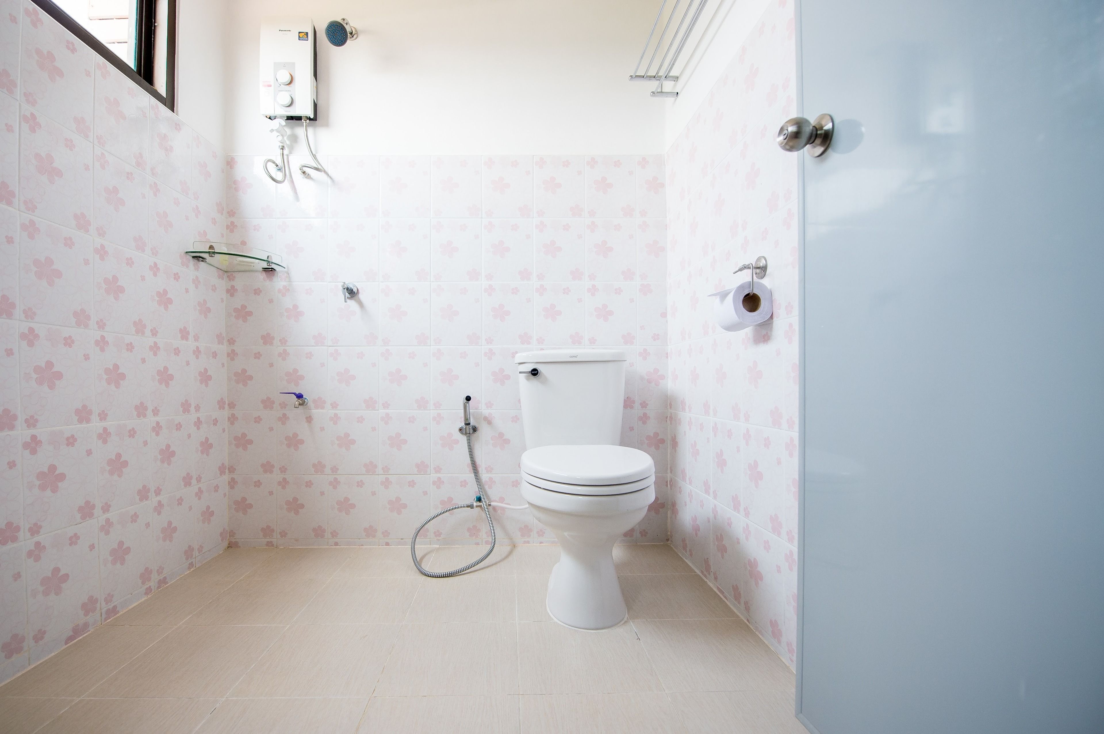 A bathroom with a toilet, a shower, and a toilet paper holder.