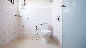 A bathroom with a toilet, a shower, and a toilet paper holder.