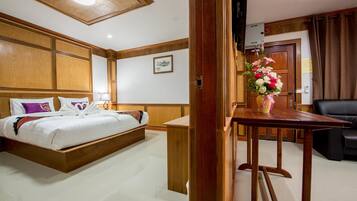 A hotel room with a wooden bed, a small table with a vase of flowers, and a leather sofa.