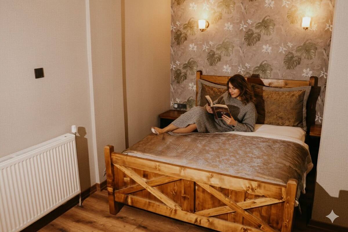 A bed with a wooden frame, a floral wallpaper, and two wall-mounted lights.