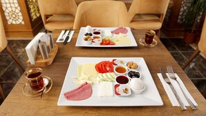 A dining table with a variety of food items and utensils, including plates of cheese, meats, and vegetables, and a cup of tea. - Zengin City Hotel (Istanbul)