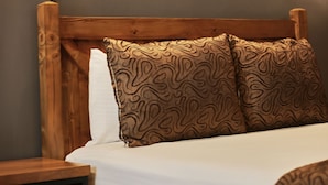 A bed with a wooden headboard, a patterned pillow, and a painting of a landscape on the wall above. - Zengin City Hotel (Istanbul)