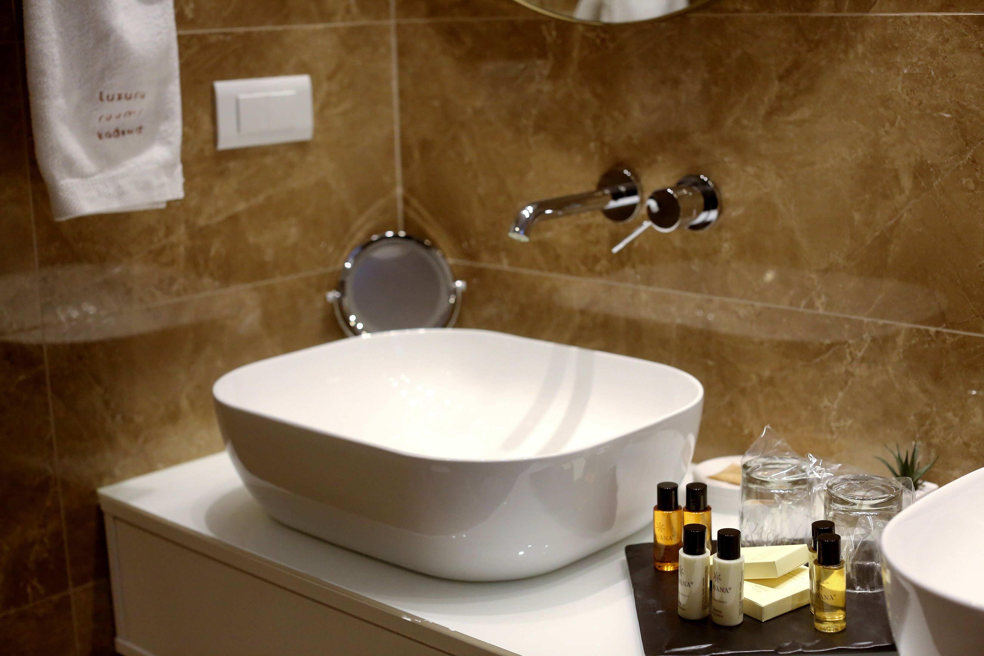 Une salle de bain avec un lavabo blanc, un miroir et des articles de toilette posés sur le comptoir.