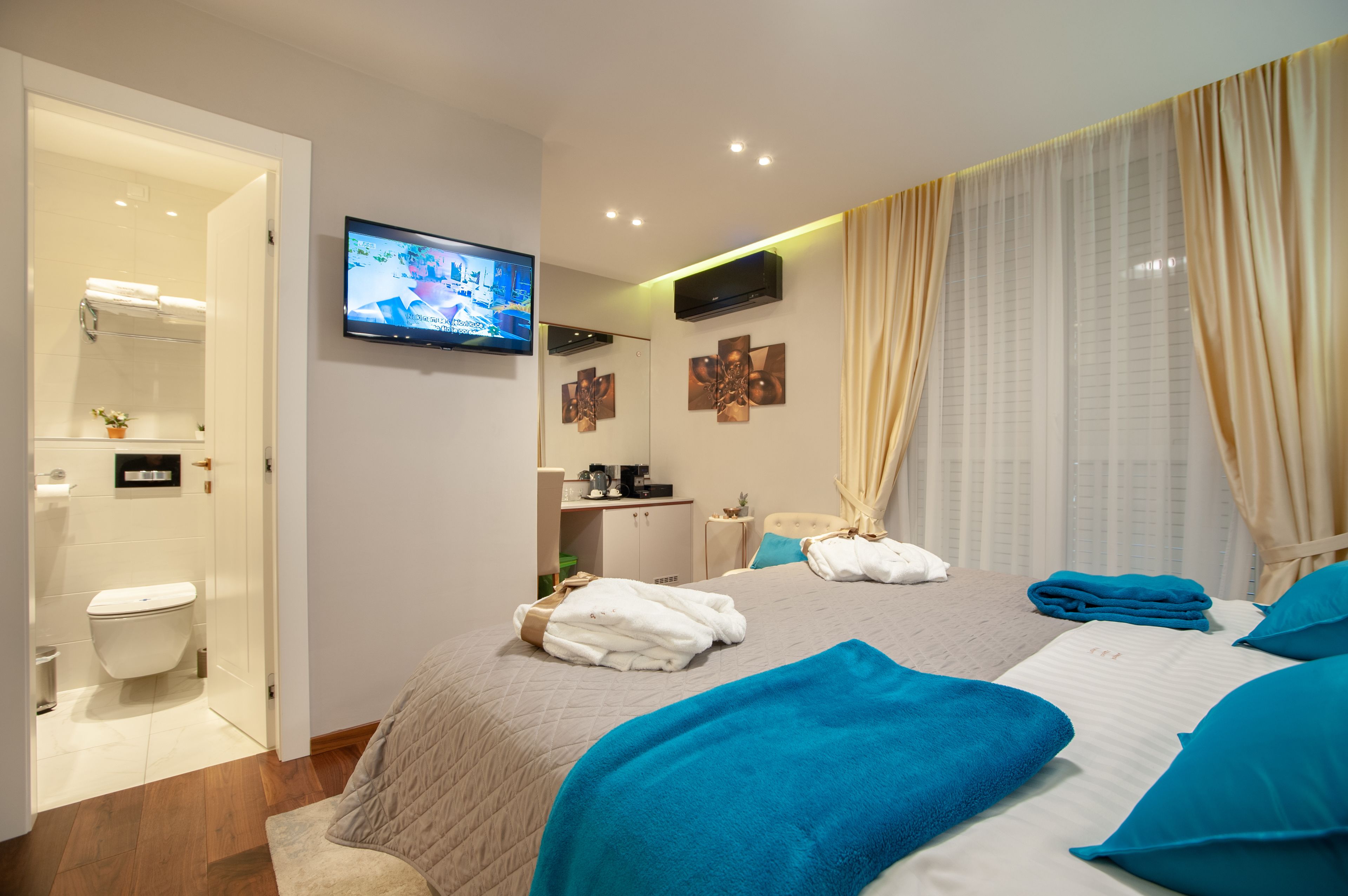 A hotel room with a bed, a TV, a bathroom, and a desk.