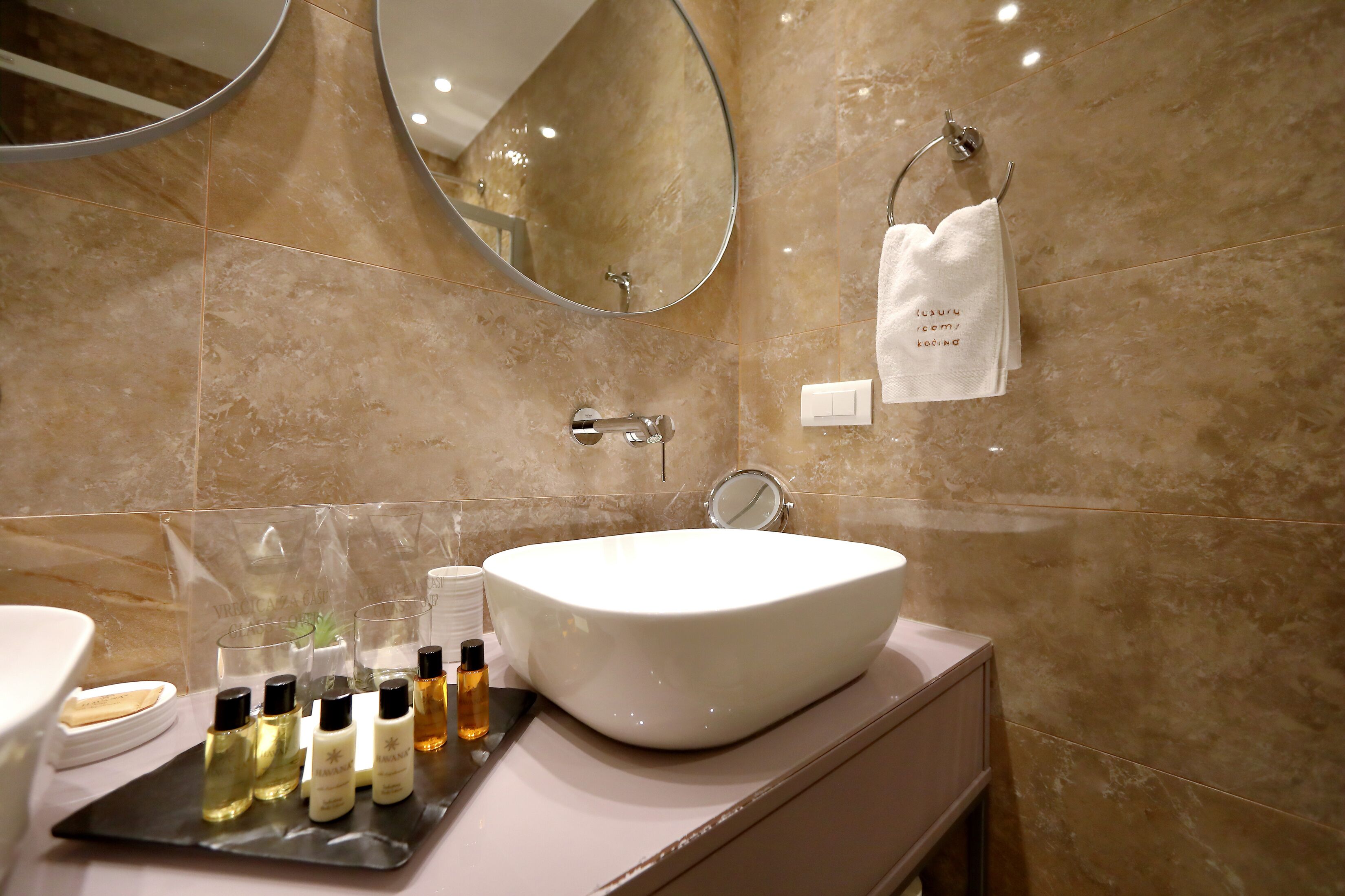 A bathroom with a large oval sink, a mirror, and a towel rack.