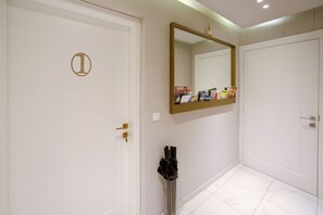 A hallway with white doors, a mirror, and a rack with umbrellas. - Luxury Rooms Kadena (Zadar)