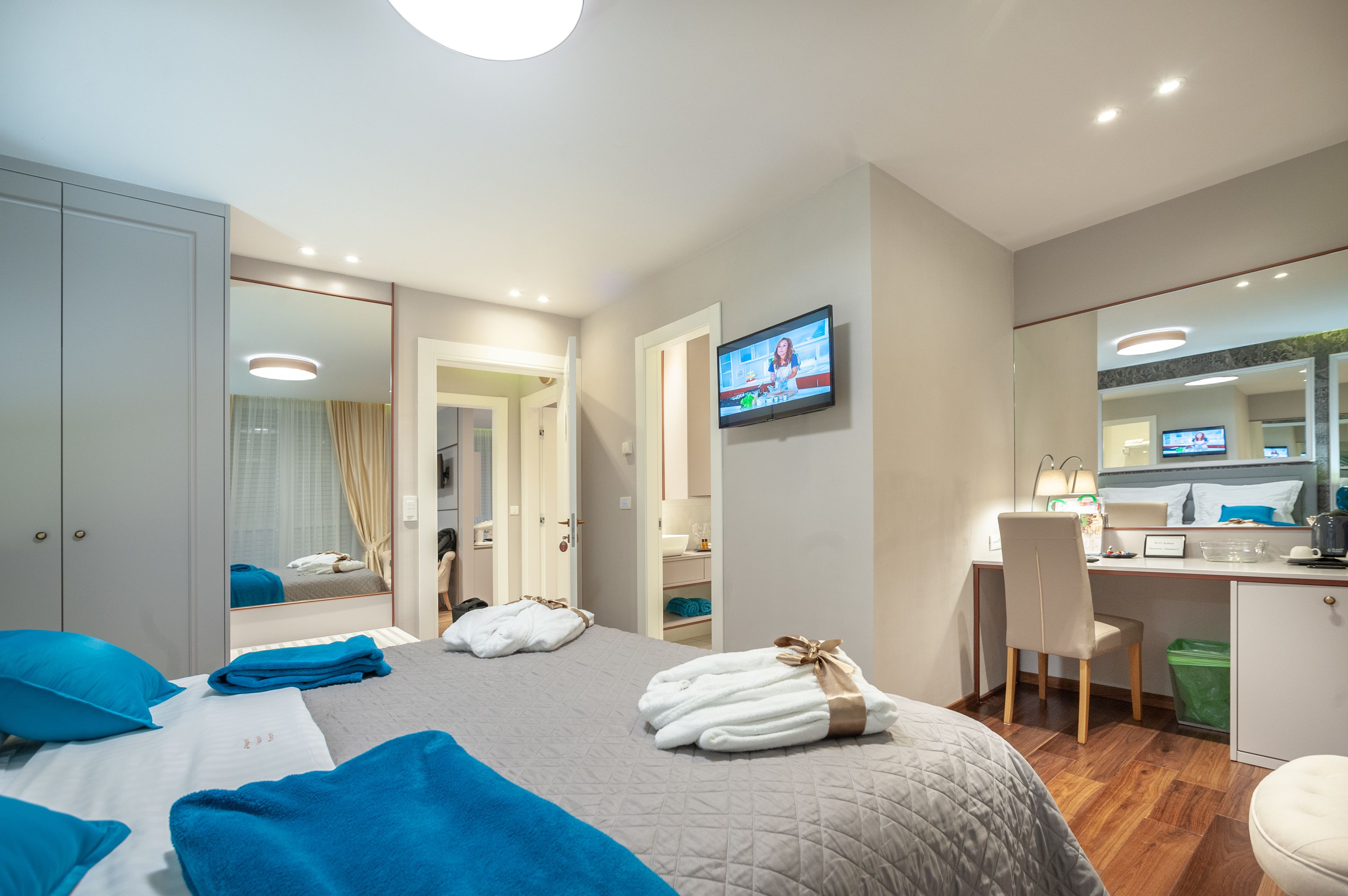 A hotel room with a bed, a desk, a chair, a TV, and a wardrobe.