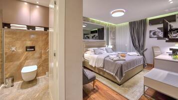 Een moderne hotelkamer met een marmeren badkamer, een bed met een grote spiegel en een bureau met een stoel.