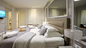 A hotel room with a large bed, a bedside table with a lamp, a TV, and a bathroom visible through an open door.