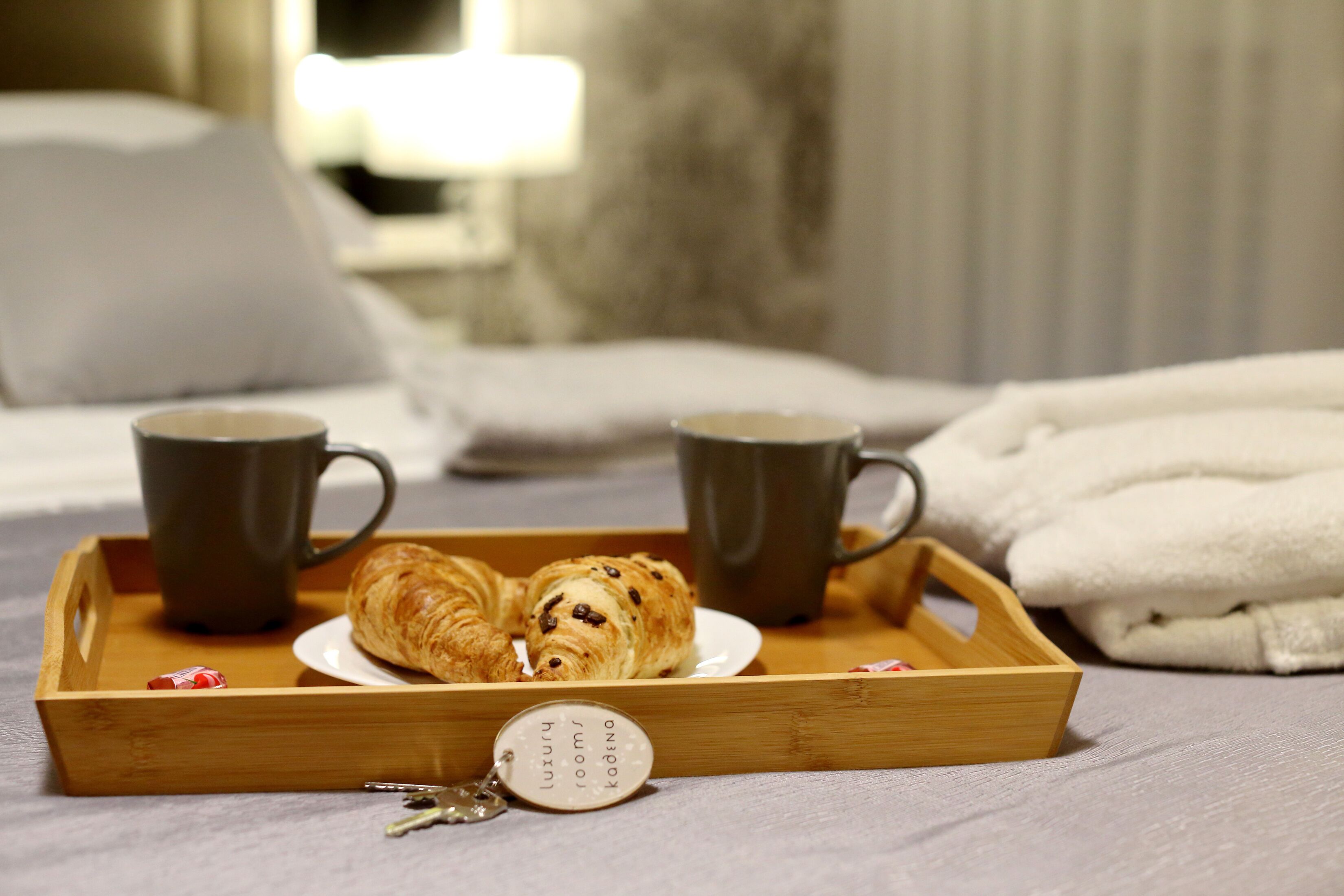 A tray with croissants and two mugs on a bed.