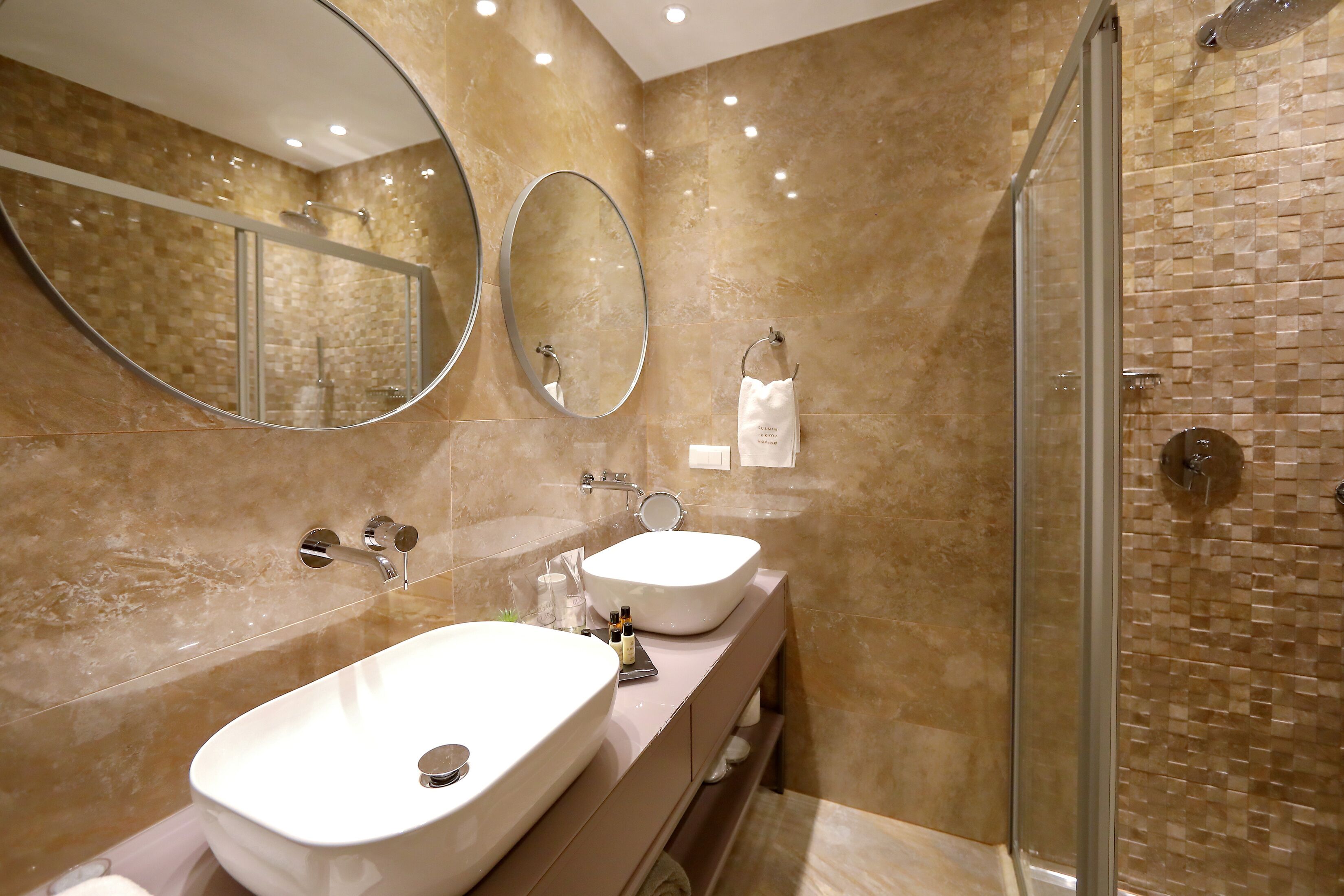 A bathroom with two sinks, a glass shower enclosure, and a large mirror.