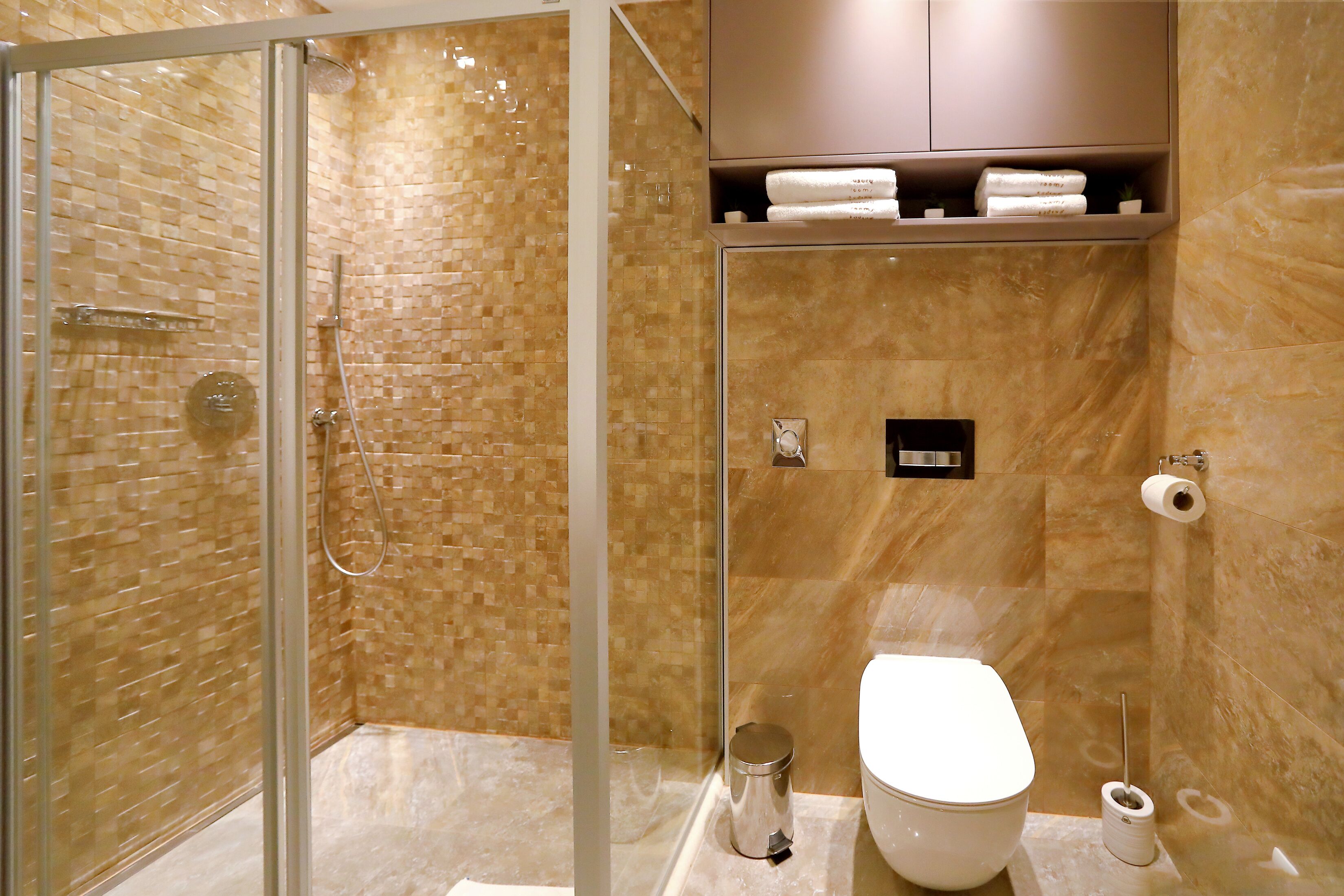 Een moderne badkamer met een douchecabine van glas, een toilet en een marmeren wand.