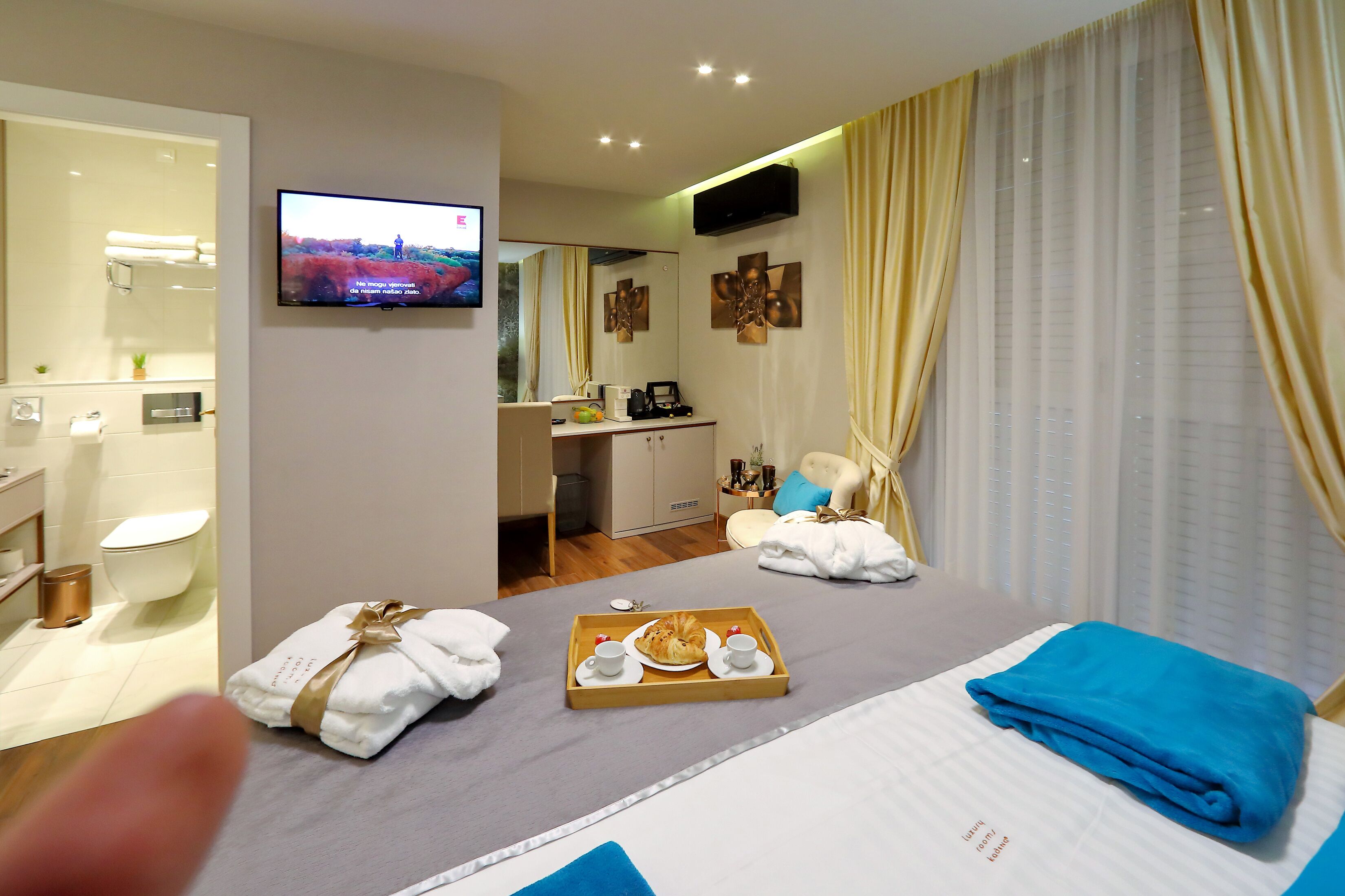 A hotel room with a bed, a TV, a desk, and a bathroom.