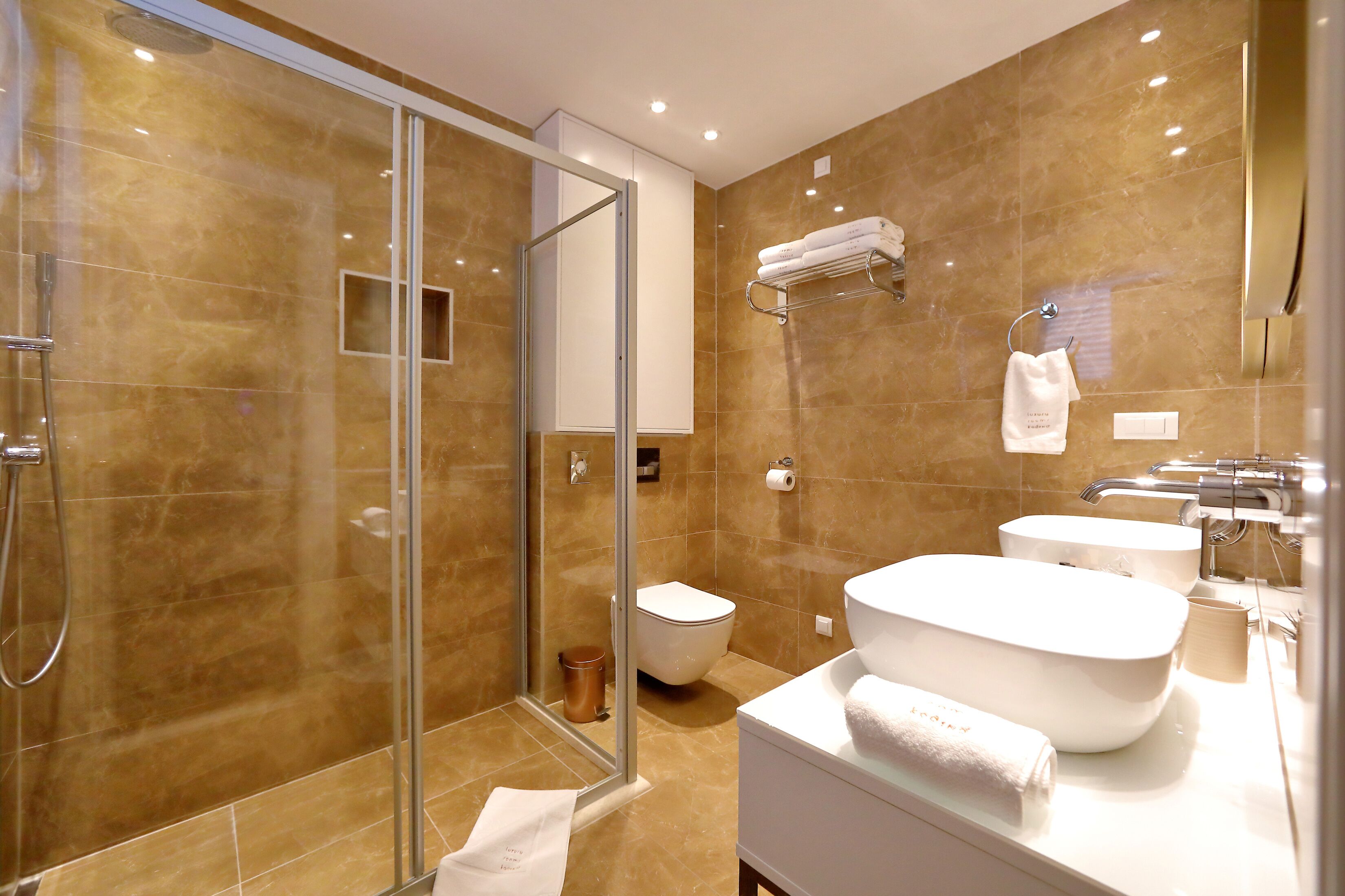 Une salle de bain moderne avec une douche à l’italienne, un lavabo blanc et une grande baignoire.