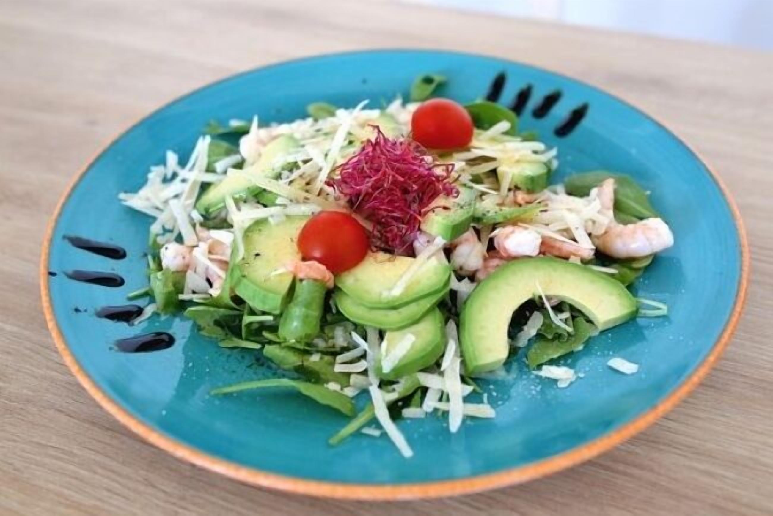 A salad on a blue plate with various vegetables and toppings.
