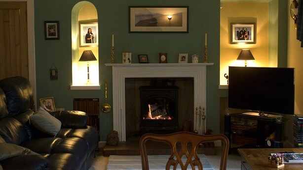 A living room with a fireplace, a sofa, a television, and a table with a vase of flowers. - Druminoch (Kirriemuir)
