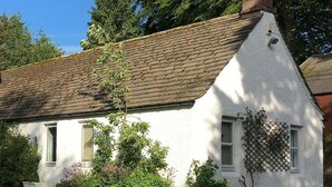 A white cottage with a sloped roof, a chimney, and a lattice window. - Druminoch (Kirriemuir)