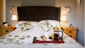 A neatly made bed with a tray of breakfast items, including a coffee pot, croissant, and orange juice. - Druminoch (Kirriemuir)