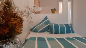 A bedroom with a bed, pillows, a bedside table, a lamp, and a mirror. - Pension Mark (Hoyerswerda)