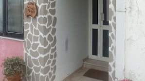 A hotel entrance with a stone facade, a sign indicating 'Hotel Without Piece', and potted plants. - Windy Place (Amari)