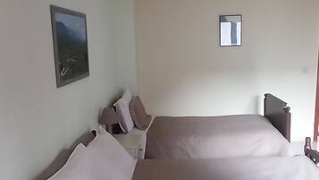 Une chambre avec un grand lit, une table de chevet, une chaise et une petite fenêtre.