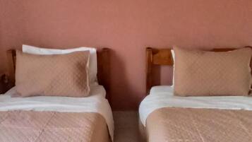 Dos camas individuales con cabeceras y pies de cama a juego, una colcha acolchada y un pequeño cuadro en la pared.