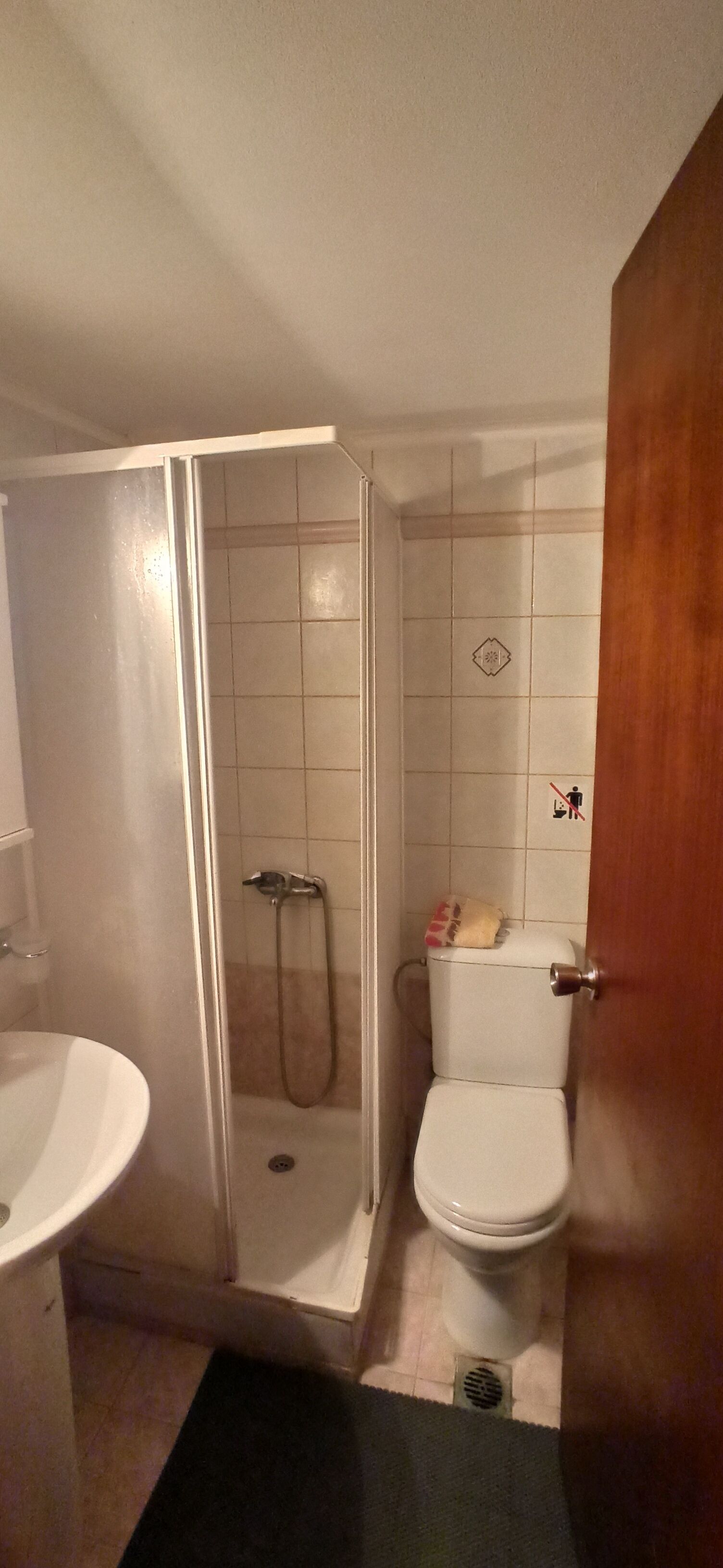 A bathroom with a shower enclosure, toilet, and sink.